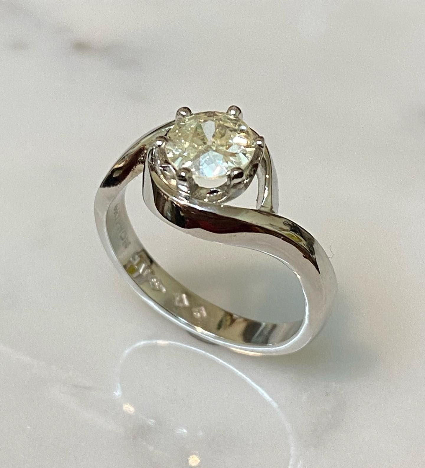 Diamond Solitaire Ring With Swirling White Gold Band on a White Surface — Burchell's Jewellers In Bowral, NSW
