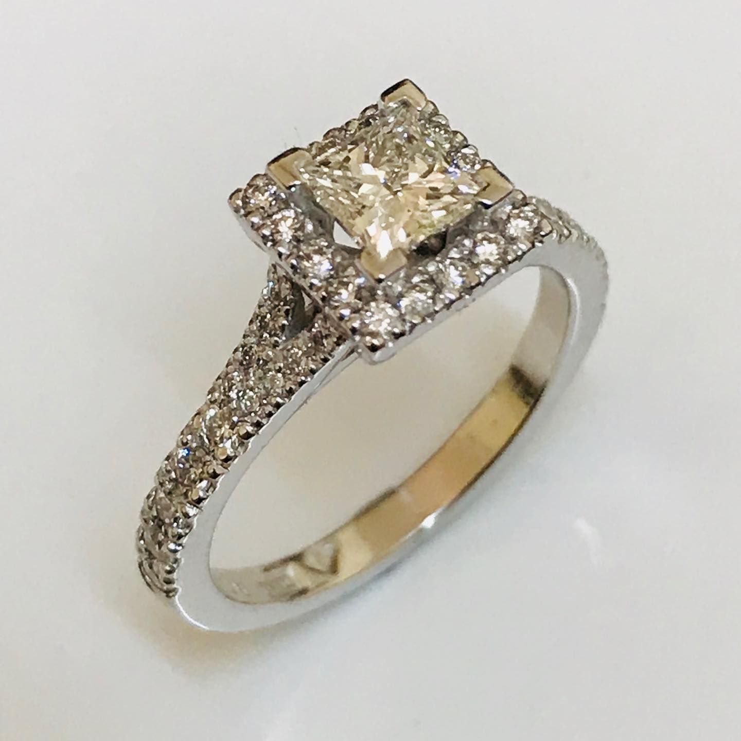 A silver diamond engagement ring with a princess-cut center stone surrounded by a halo, set on a pavé diamond band. — Burchell's Jewellers In Bowral, NSW