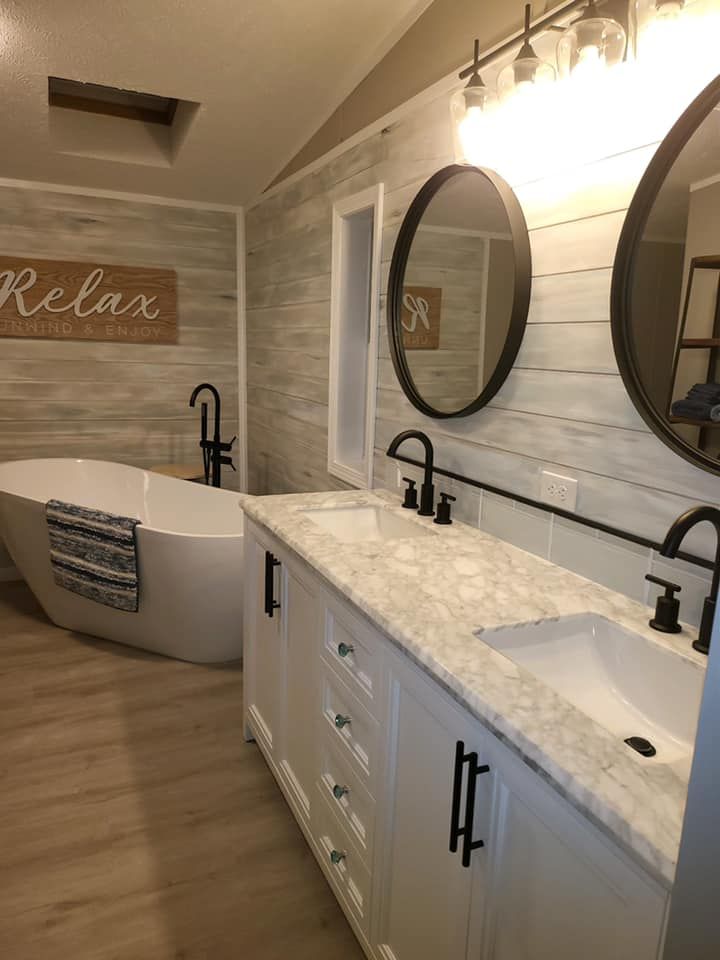 A bathroom with a bathtub , sinks , mirrors and a sign that says `` relax ''.