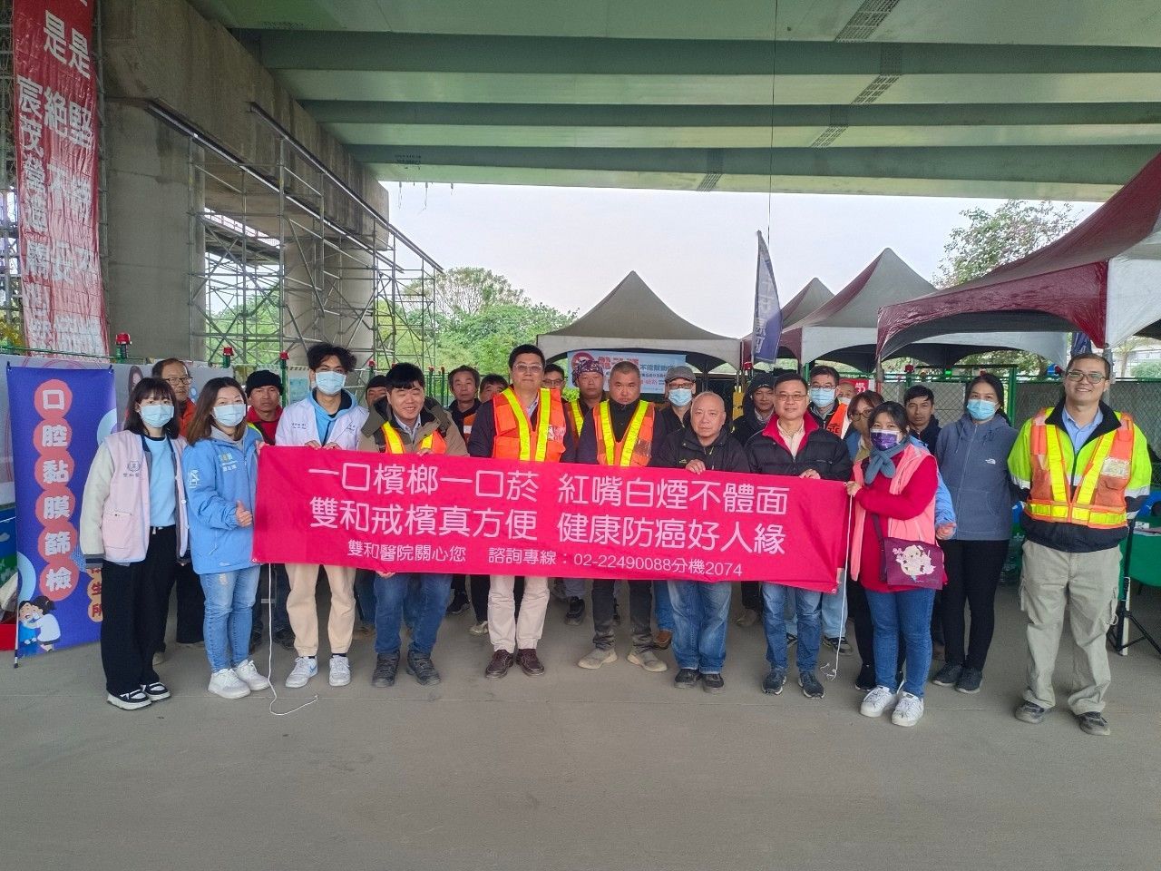 在一次公眾宣傳活動中，戴著口罩的志工們在天橋下舉著一條紅色橫幅。