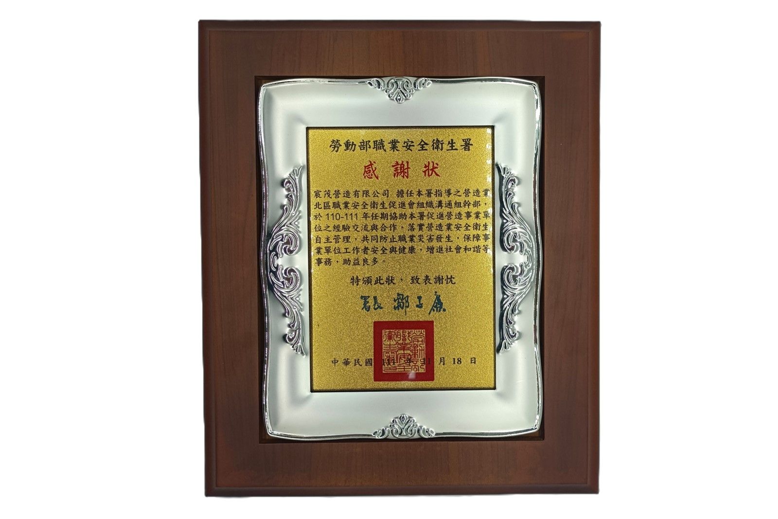 裱框金色獎牌，內有中文文字和紅色印章，置於木質背景上