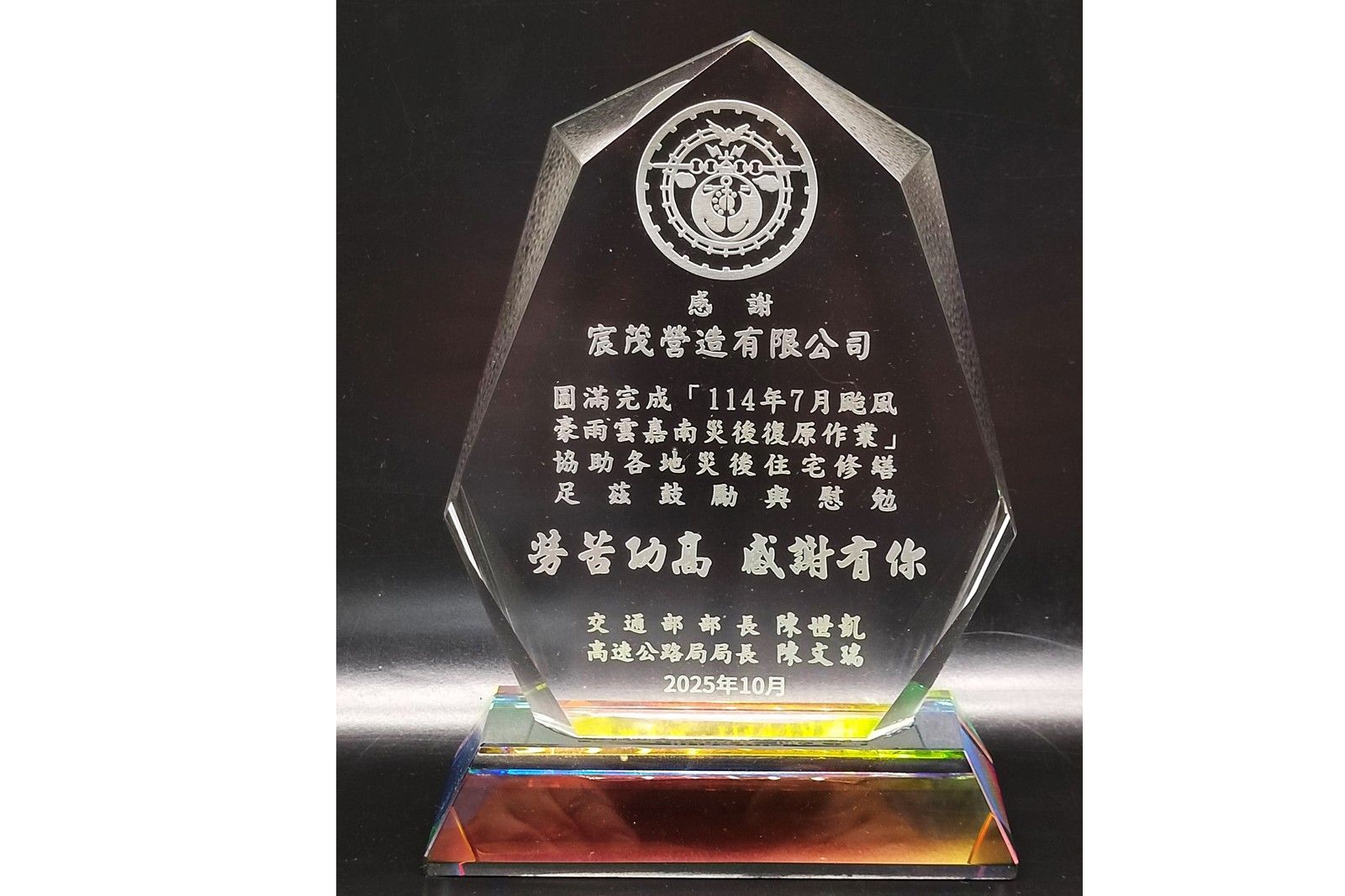 透明玻璃獎杯,底座為彩色,黑色背景,上面刻有中文銘文。