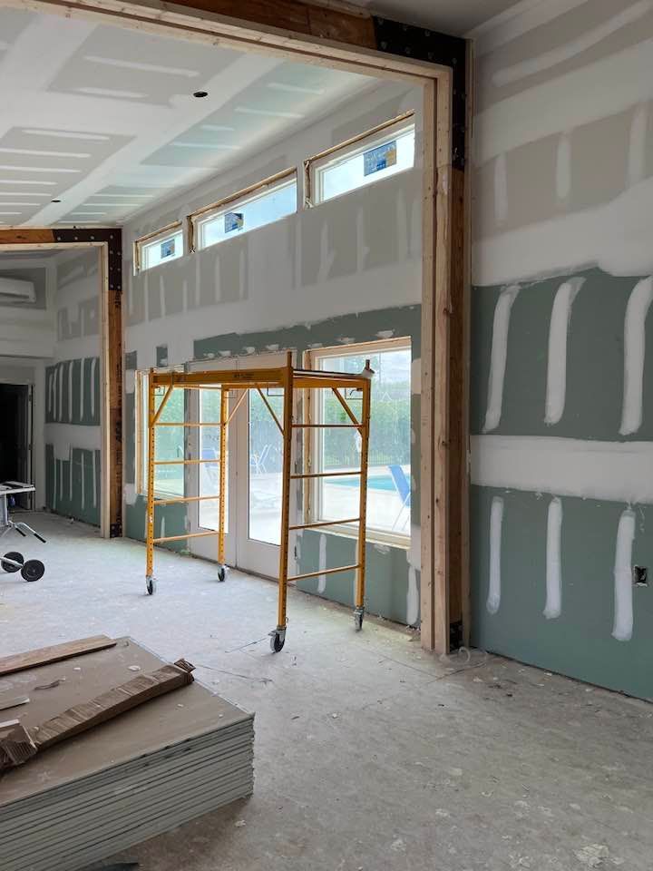 Interior room under construction with drywall and scaffolding.