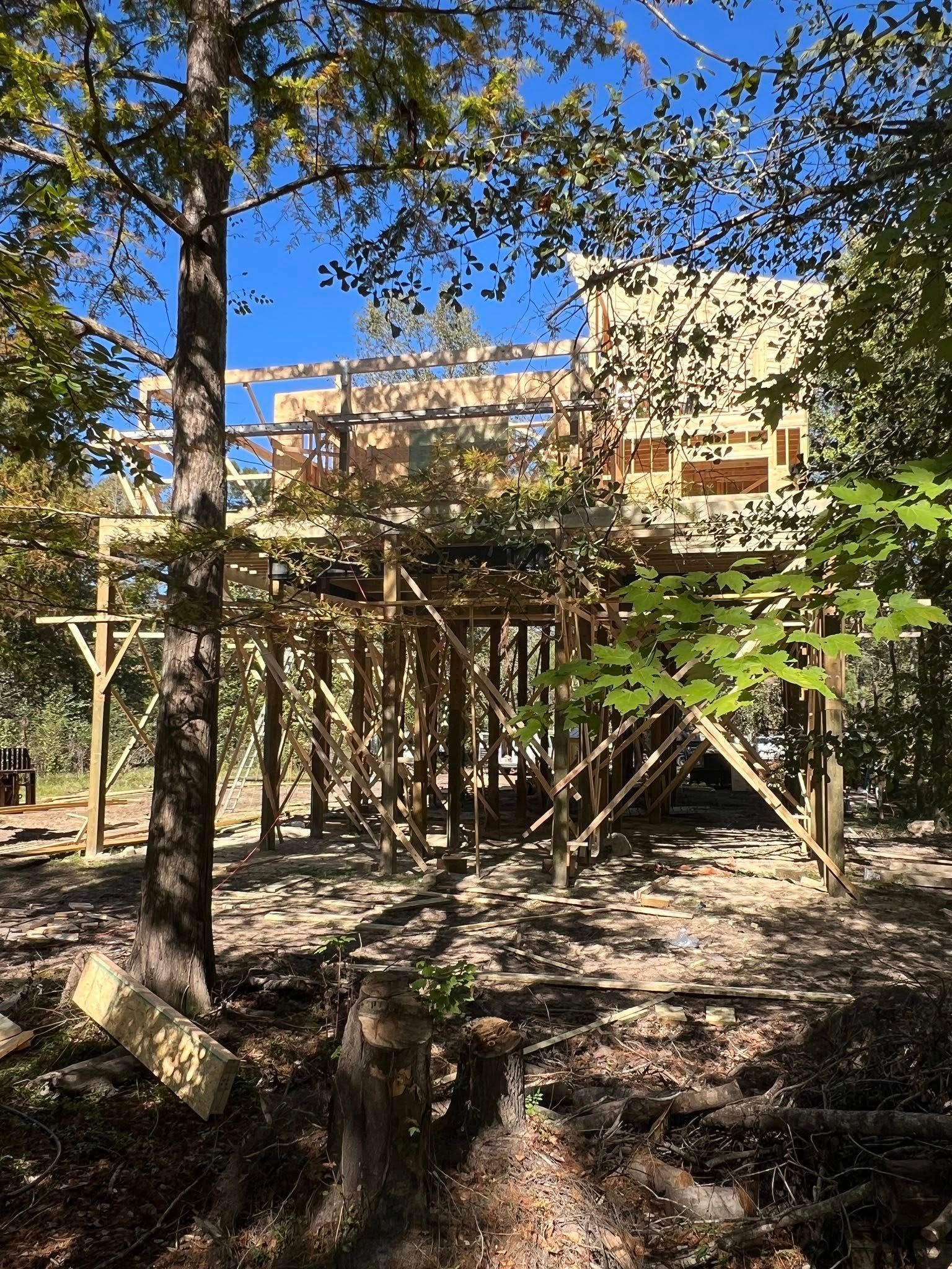 Wooden structure being built in a forest setting with beams and platforms.