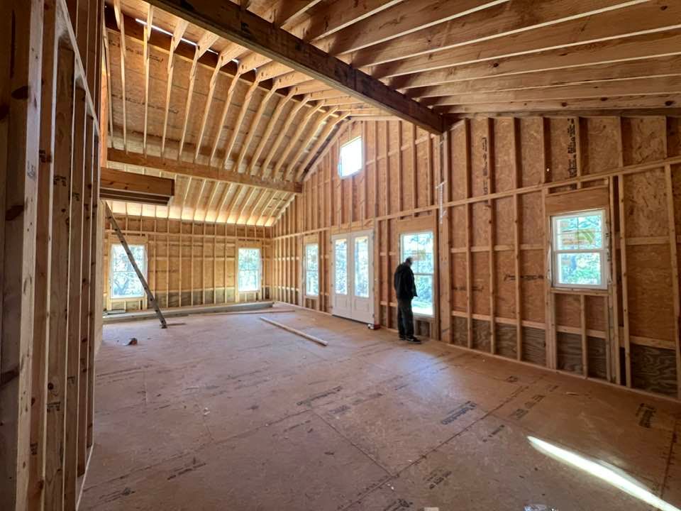 Interior of a building under construction, wooden frames, vaulted ceiling, person by a window.
