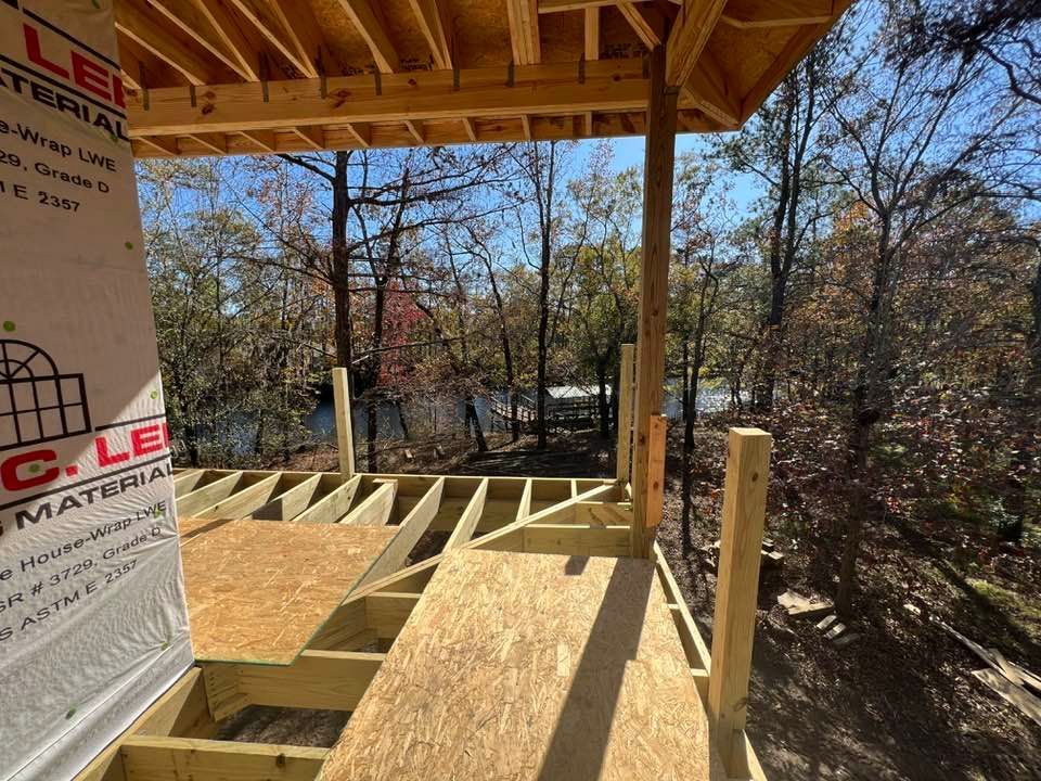 Construction of a wooden deck with a partial roof overlooking a body of water.