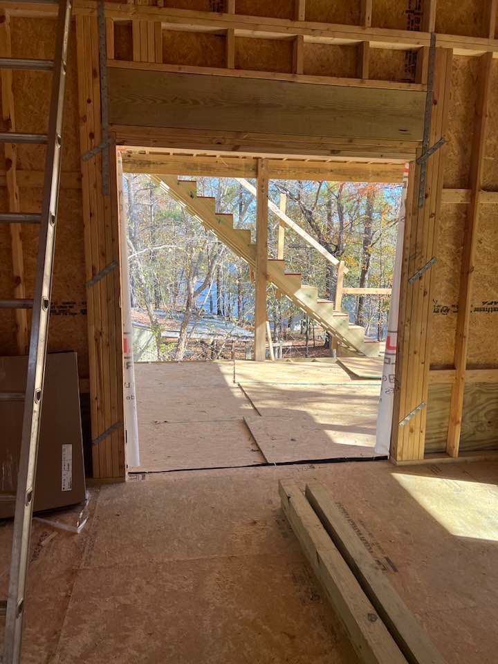 Interior view of a building under construction, looking out at a staircase.  Wooden framing is visible.