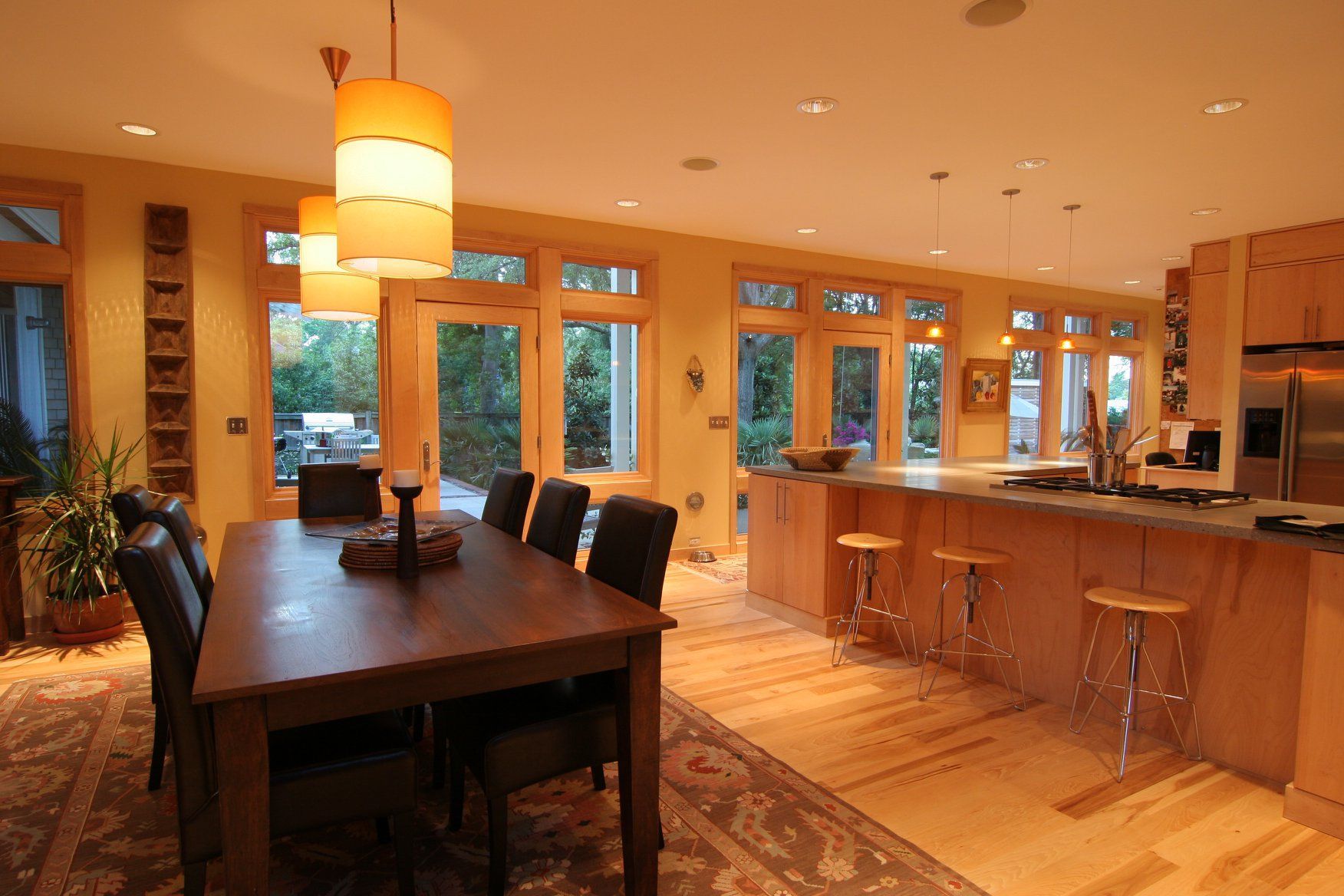Dining room with a wooden table and chairs, adjacent to a kitchen with a breakfast bar.
