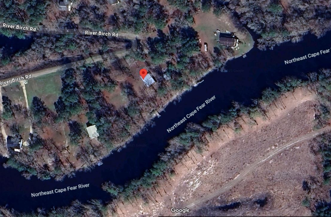 Aerial view: building near a river surrounded by trees.
