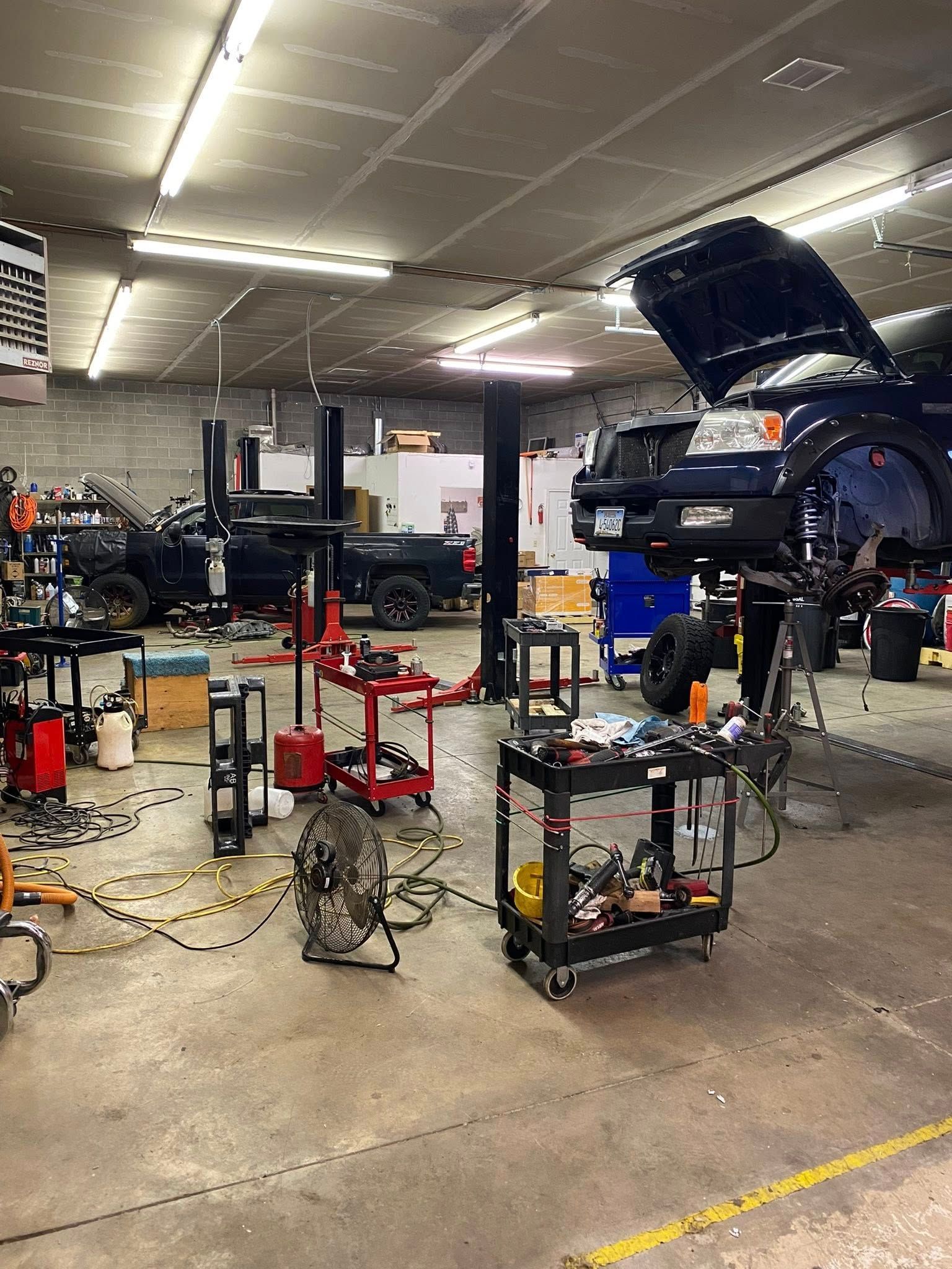 Auto repair shop with a car lifted on a hoist and tools scattered on the floor