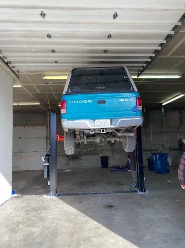 Blue Dodge pickup lifted on a vehicle hoist in a garage