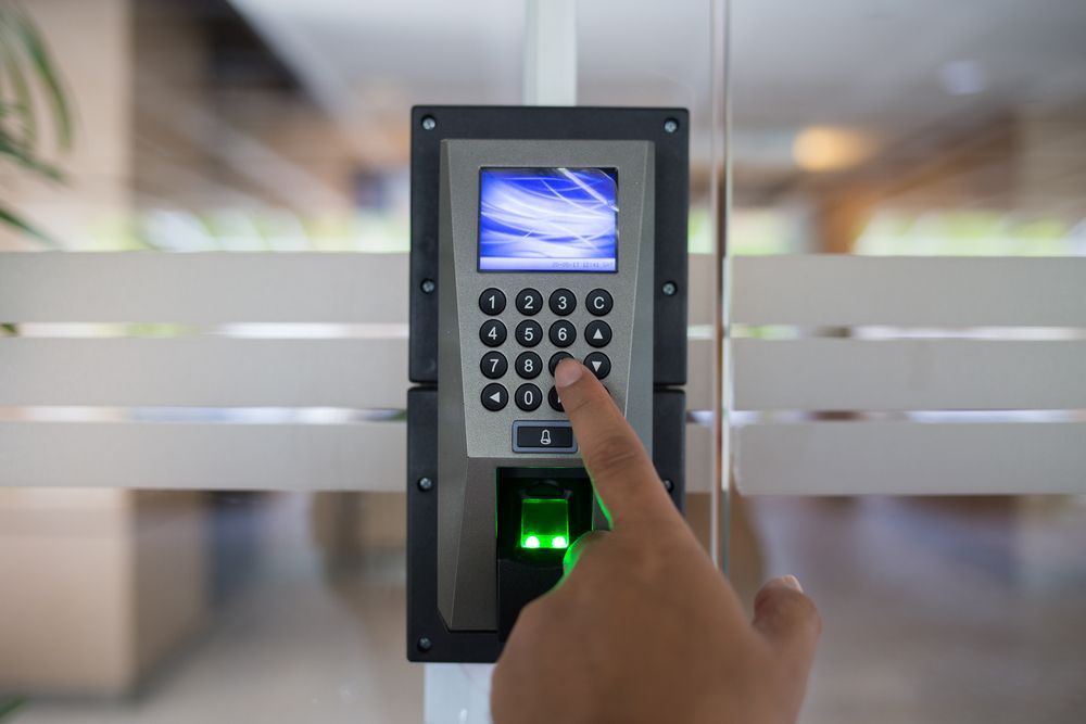 Hand Entering a Security Code on Keypad; a Fingerprint Scanner is Below — Powered By JBES In Sandgate, NSW