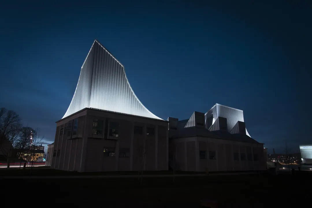 Moderne bygning med oplyst tagstruktur og arkitektonisk facadebelysning.