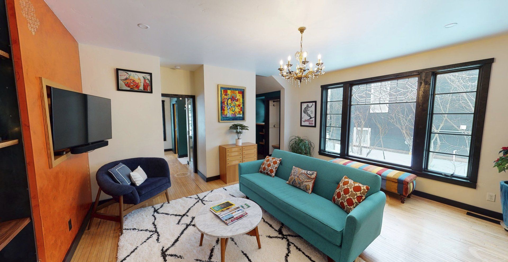 Blue couch staged in the middle of the living room with windows behind and a tv in front.