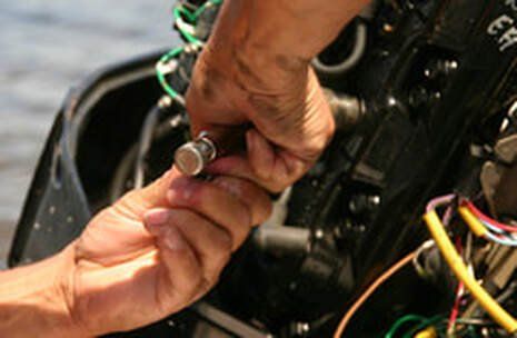 Hands working on a boat engine, holding a small metal part.