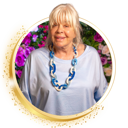 Lachende vrouw in een witte top met blauwe ketting, omlijst door een gouden cirkel met kleurrijke bloemen op de achtergrond.