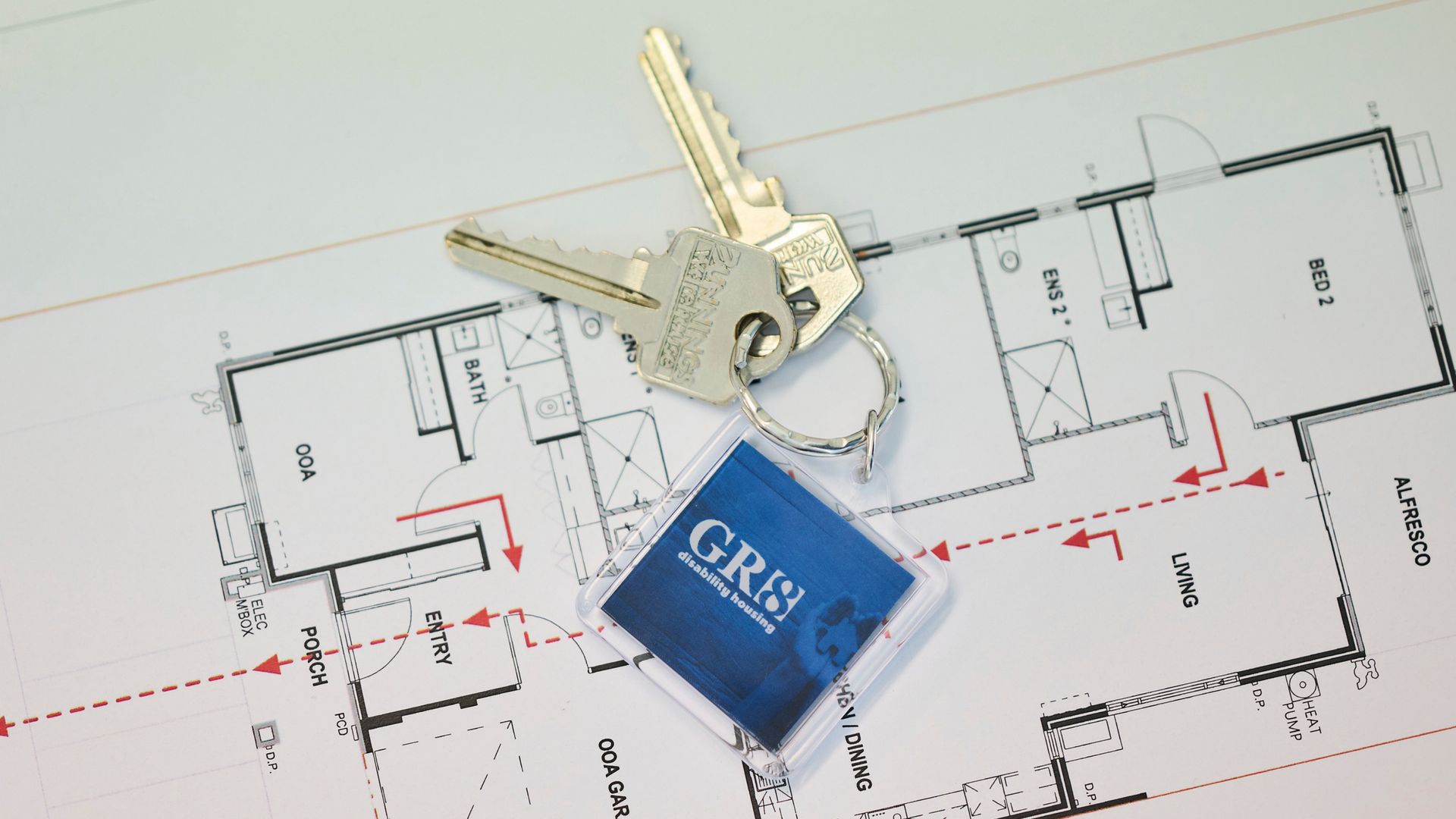 Keys and a blue house keychain resting on a house floor plan drawing.