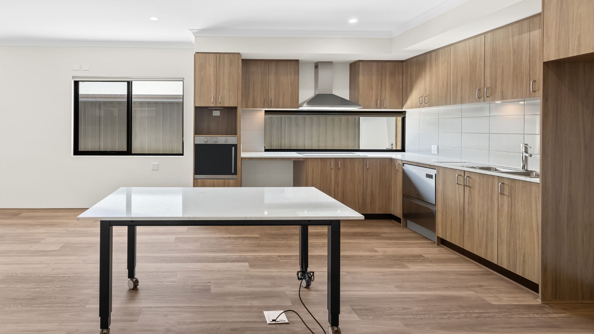 Modern kitchen with wood cabinets, stainless steel appliances, and a white table.
