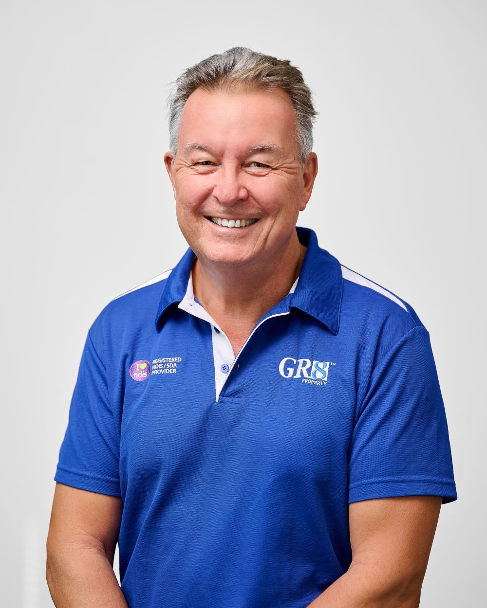 A man in a blue polo shirt is smiling for the camera.