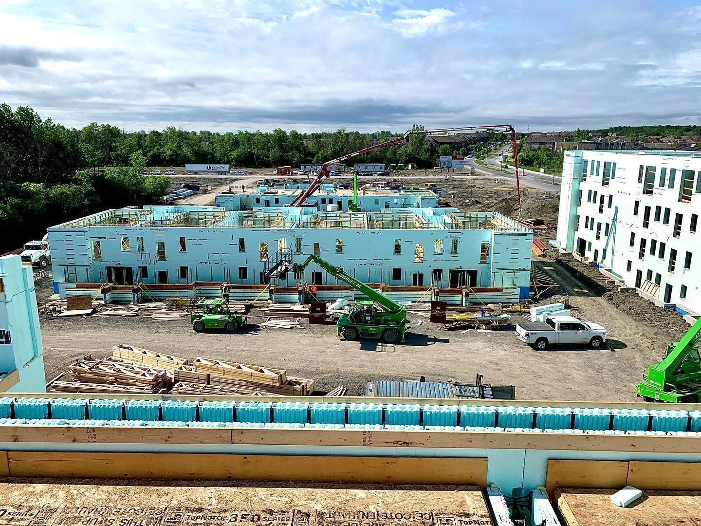 Construction site with several buildings under construction; concrete being poured; blue foam panels visible.