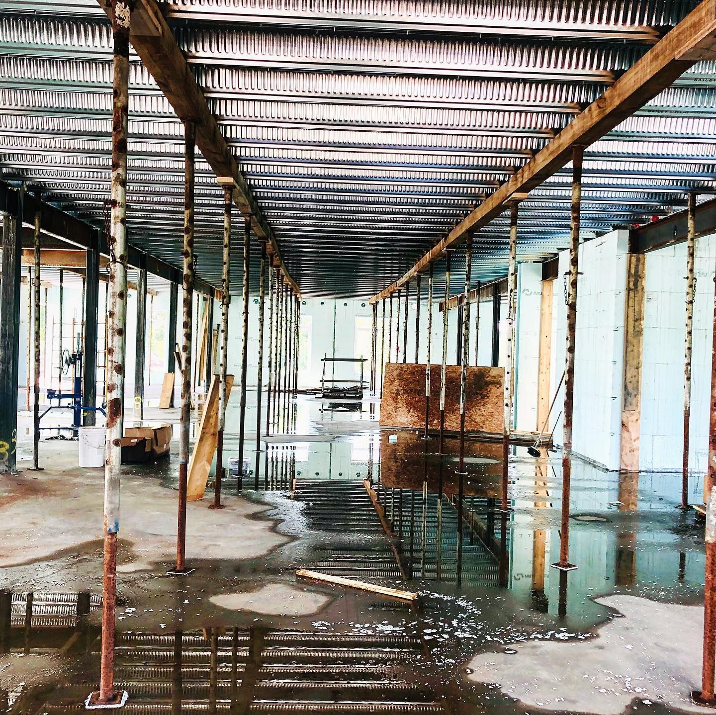 Interior of a construction site with supports, corrugated ceiling, and standing water.