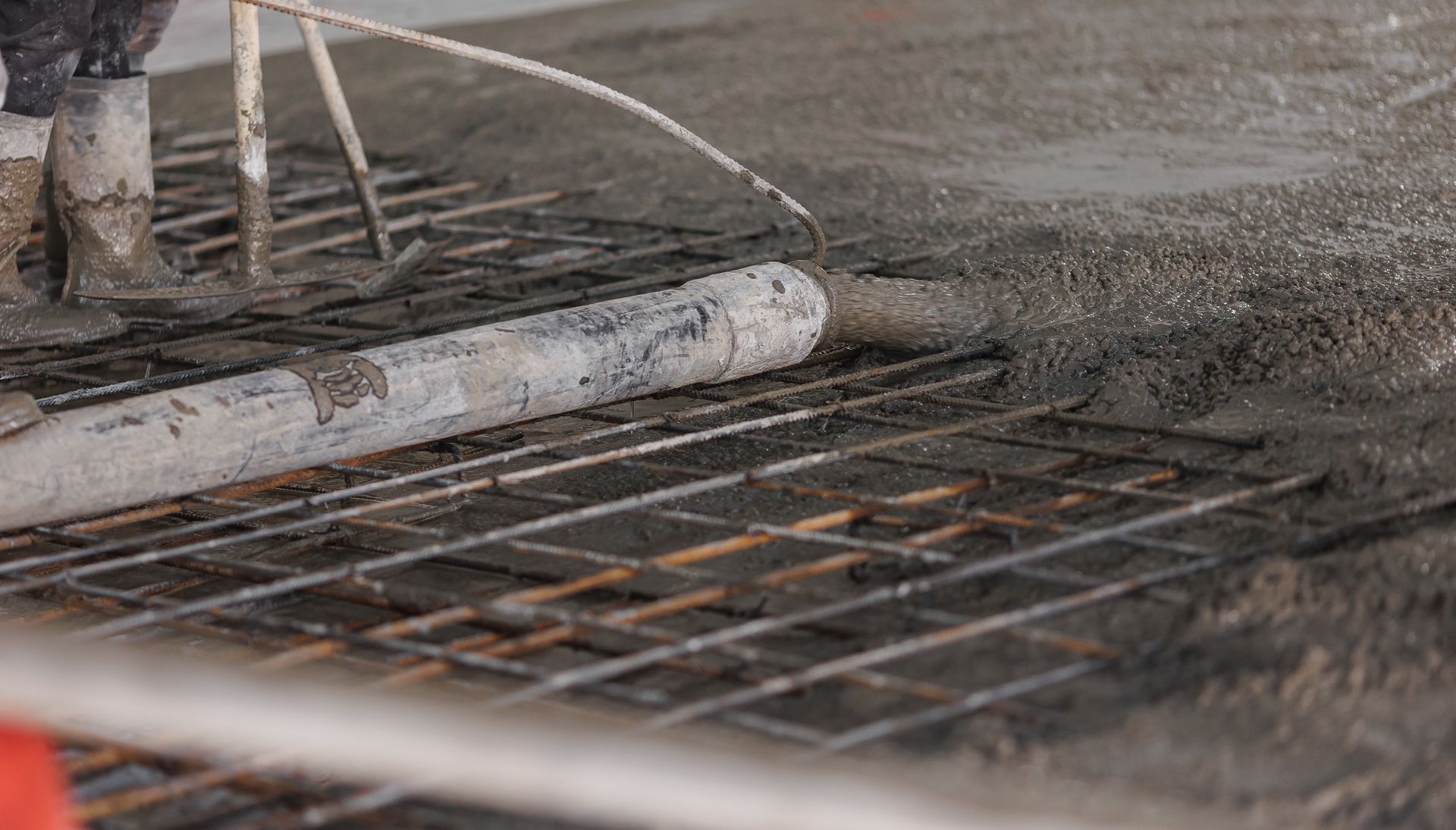 Pouring wet concrete over a rebar grid during construction.