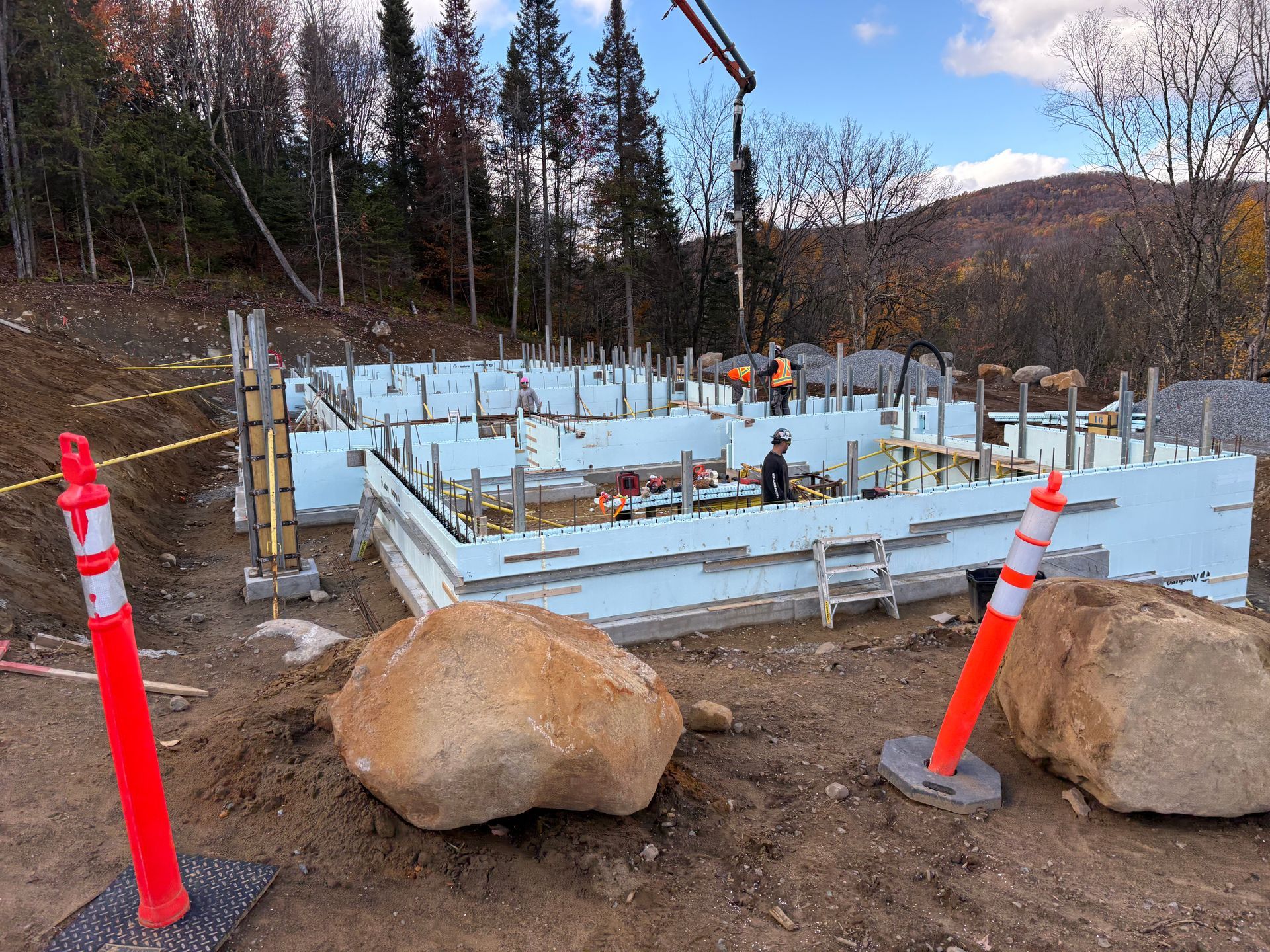 Construction site with insulated concrete forms, orange traffic cones, and workers.