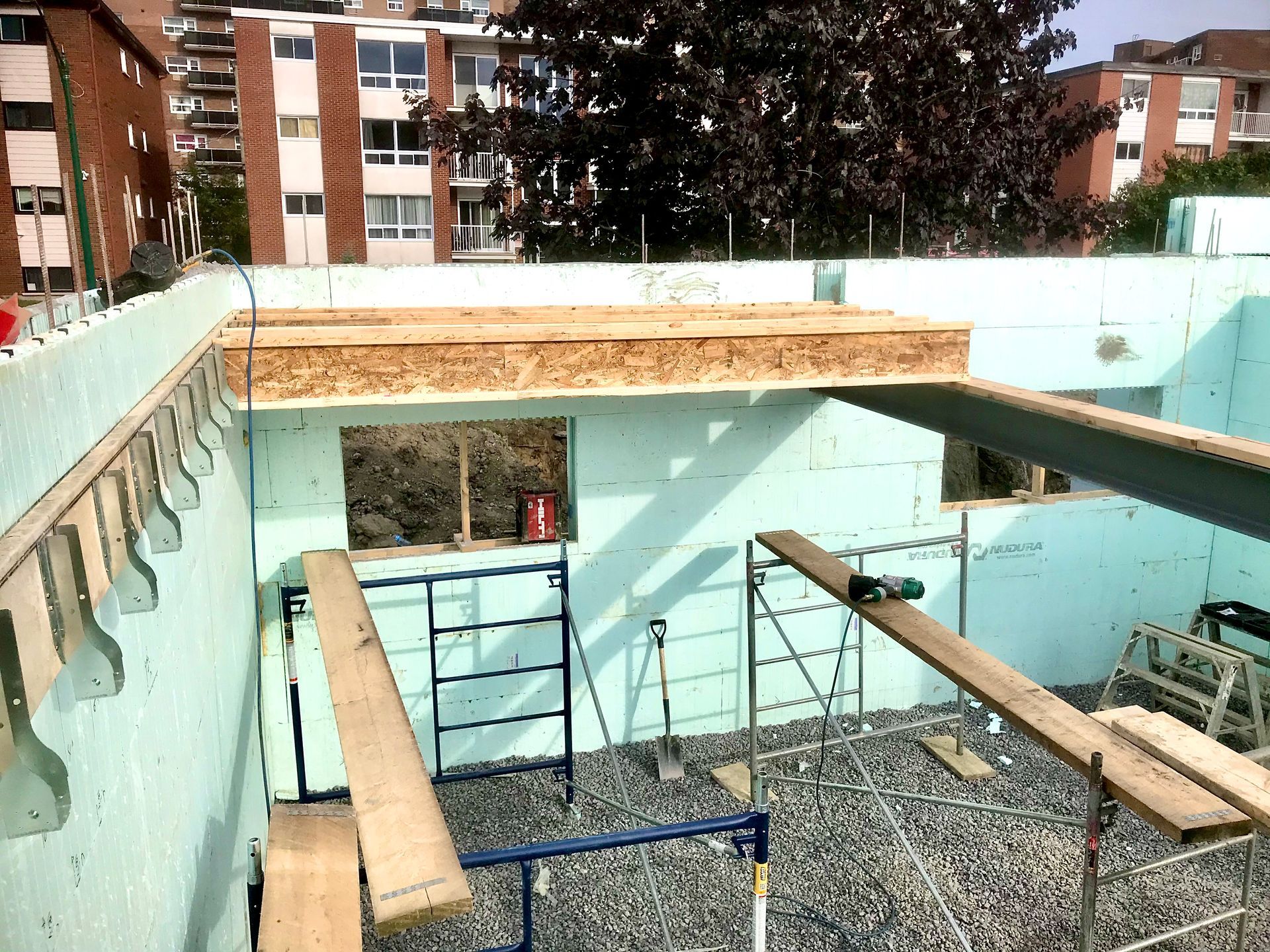 Construction site with light blue insulated concrete forms, OSB, and scaffolding.