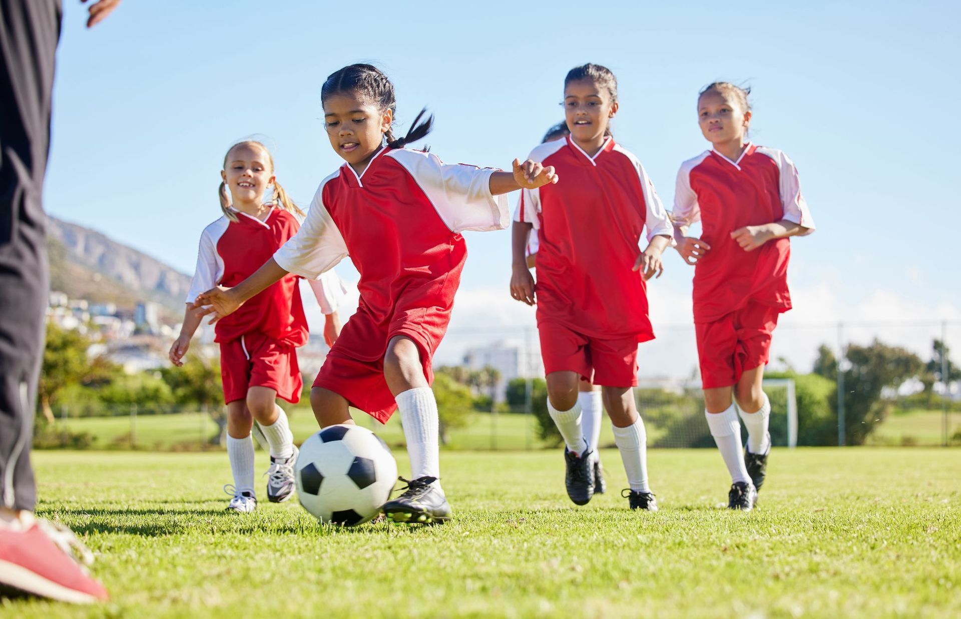 A group of young girls are playing soccer on a field.