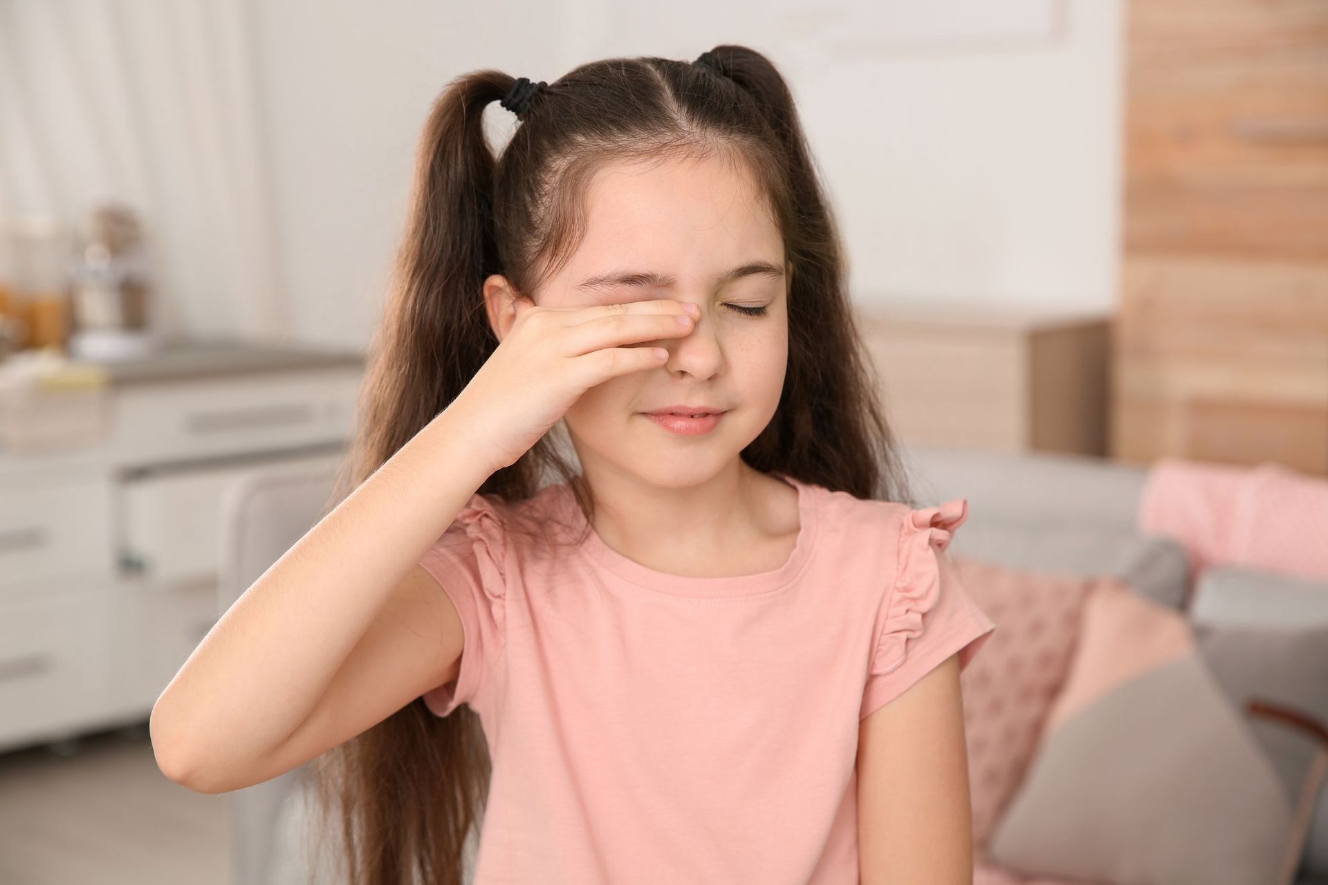 A little girl is covering her nose with her hand.