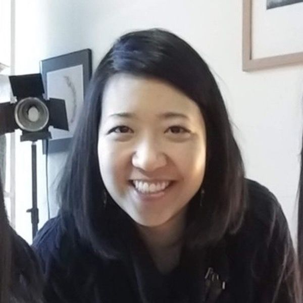 A woman in a black shirt is smiling in front of a camera.