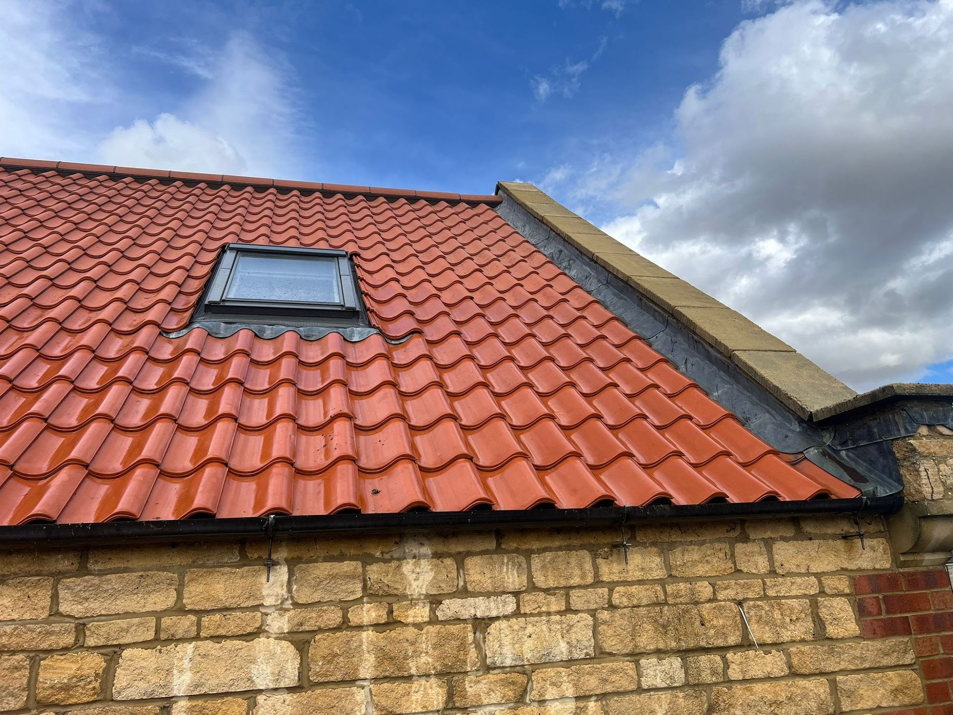 Man pressure washing a moss-covered roof. Clear blue sky.