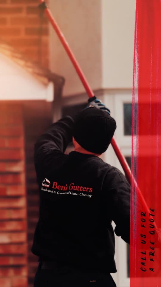 Person on a ladder cleaning gutters with a long brush; building exterior in background.