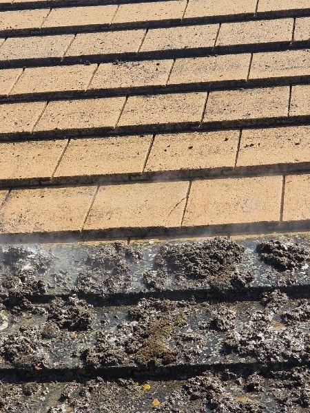 Roof tiles being cleaned; water spraying from a pressure washer removes dirt and debris.