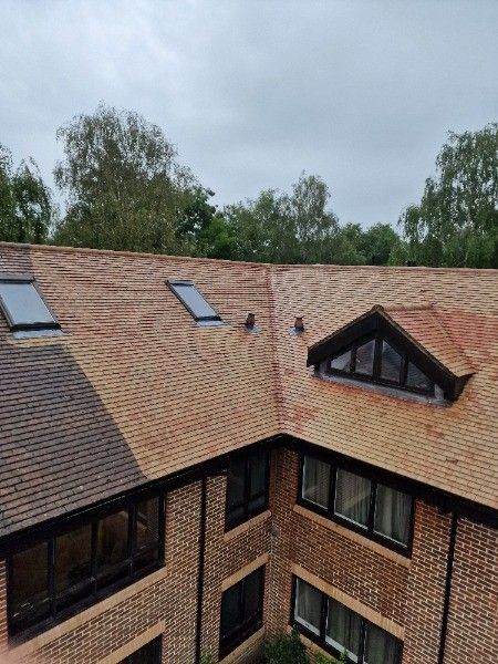 Brick building exterior with clay tile roof and skylights under overcast sky.