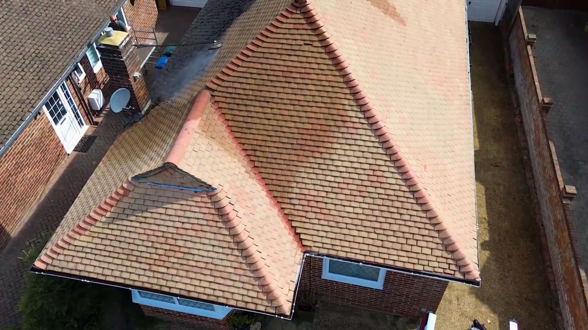 Aerial view of a house with a red-tiled roof. Two white-framed windows are visib