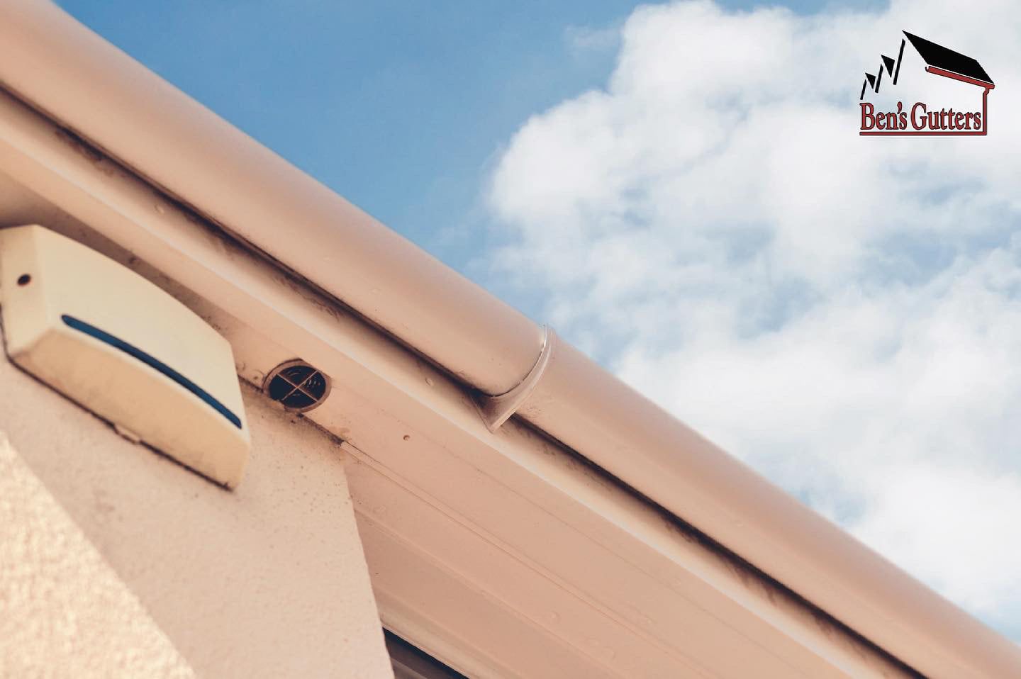 Beige gutters along a building with a blue sky background.