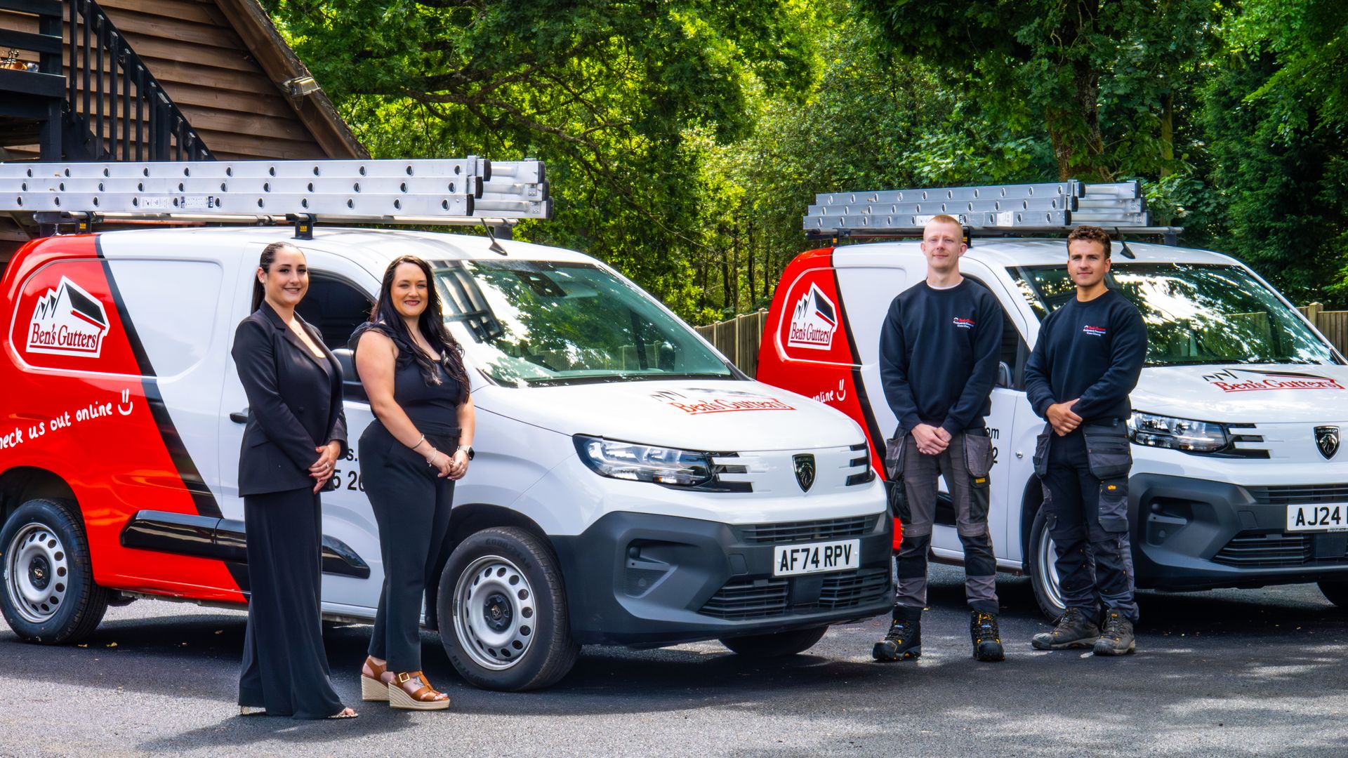 Two vans with company logos, parked, with four people posing in front.
