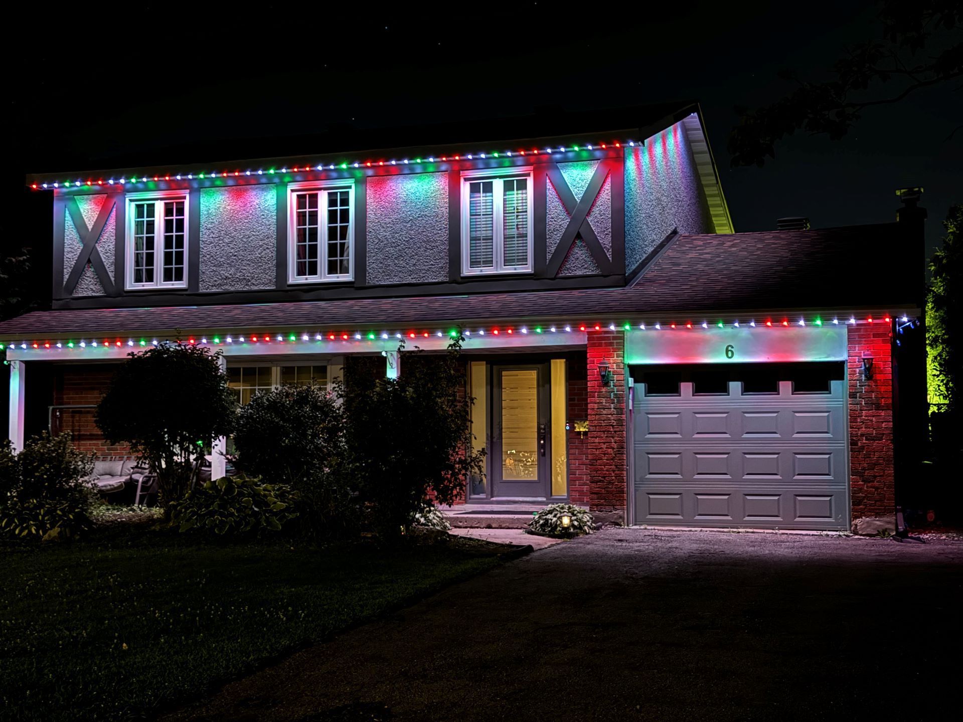 Permanent Christmas roofline lighting in red and green on a two-story Tampa home
