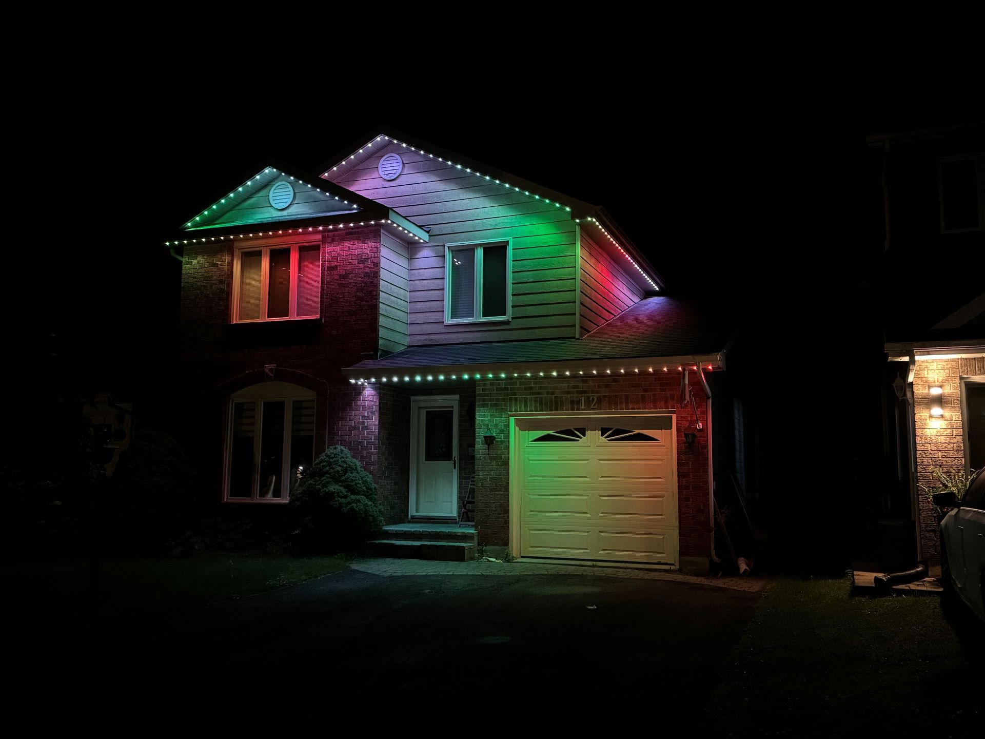 House at night lit with colorful pink, green, and purple holiday lights