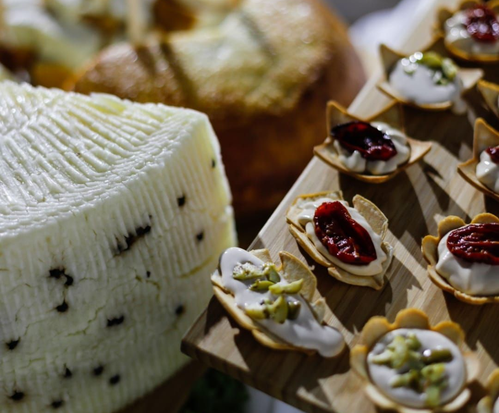 Un assortimento di formaggi e cracker farciti su un vassoio, tra cui uno spicchio di formaggio bianco e piccoli stuzzichini.