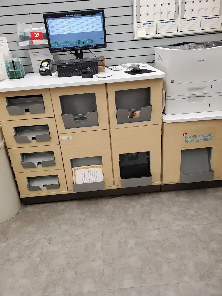 Medical office counter with computer monitor, cabinets, printer, and supplies on a gray floor.
