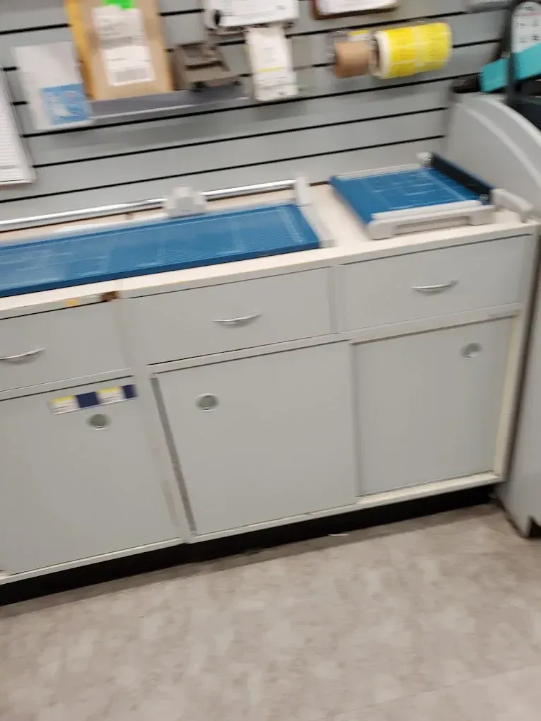 White cabinet with blue trays and supplies on a counter in a store or lab workspace.