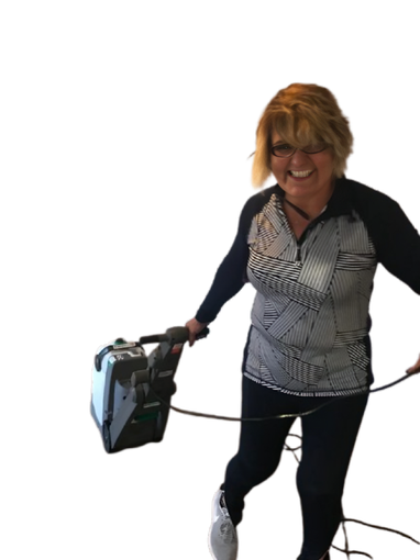 Woman holding a small vacuum cleaner and cord, standing against a white background.