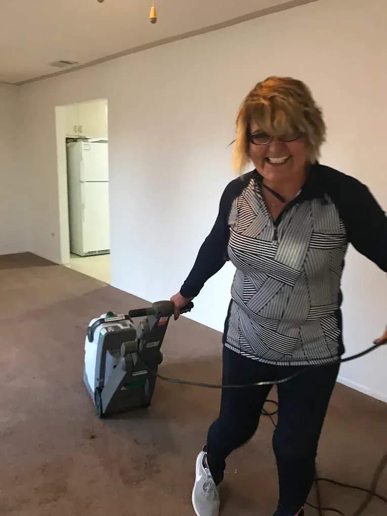 Person smiling while pulling a wheeled bag in an empty room