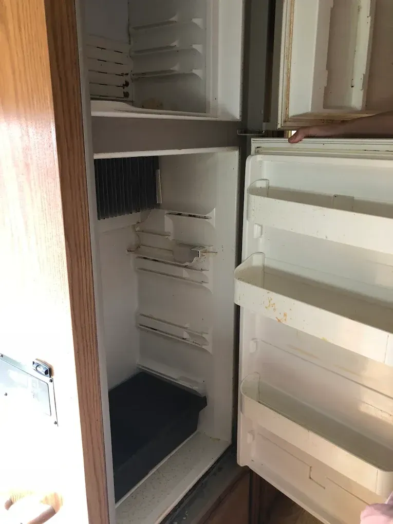 Open refrigerator with empty shelves and freezer compartment, showing a mostly bare interior.