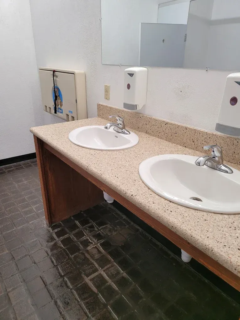 Restroom counter with two white sinks, beige countertop, and mirrors above