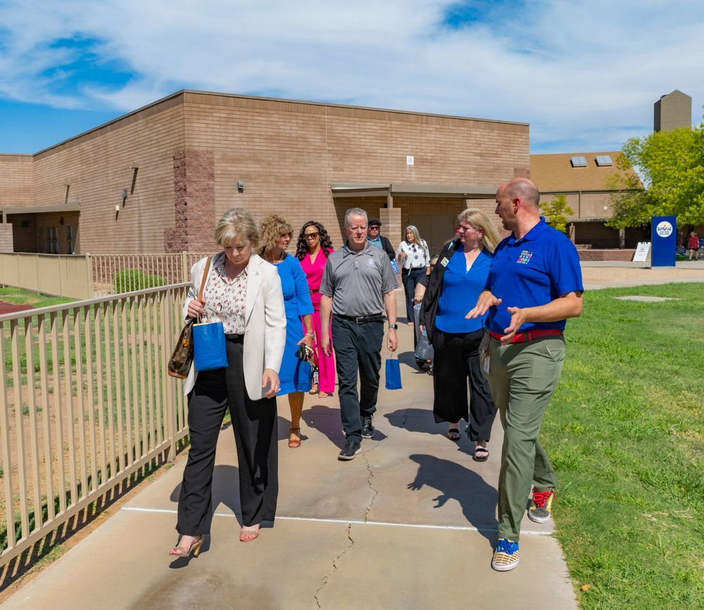 People walking on a sidewalk by a brick building on a sunny day