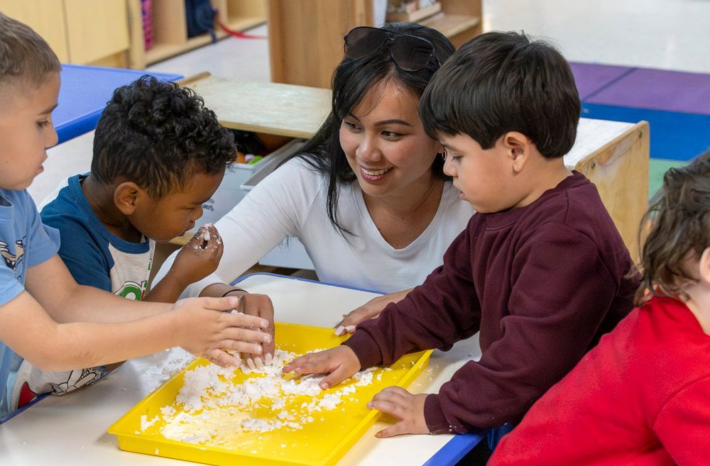 Teacher and children playing with dough at a classroom table
