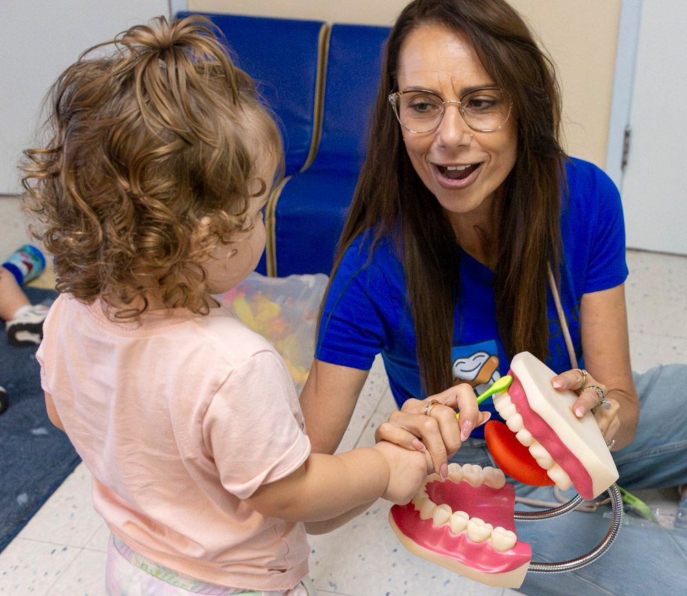 Woman demonstrating dental model to child in a classroom setting